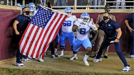 Michael Carter (8) and Brian Anderson (68) and the Tar Heels take to the field to face Florida State.
