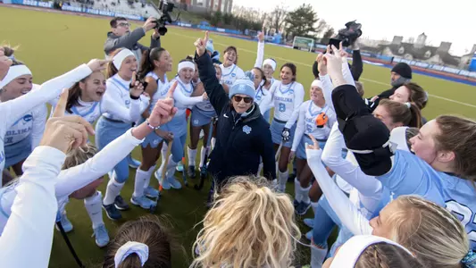 Karen Shelton huddles with the team on the field.