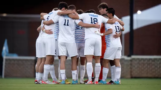 The Tar Heels huddle on Dorrance Field.
