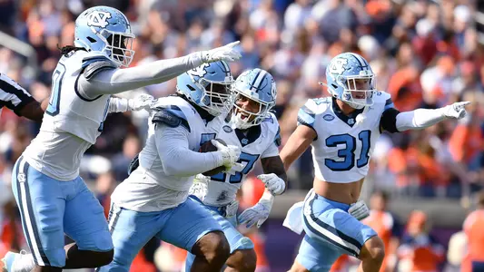 Graduate student Kaimon Rucker, center, and Tar Heel defenders run toward their bench after getting a turnover against Virginia Saturday at Scott Stadium in Charlottesville, VA.