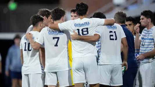 The Tar Heels huddle near the bench.