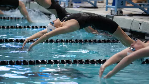 Senior Emma Karam pushes off the start of the 100-yard backstroke against Boston College and UNC-W at Koury Natatorium Friday afternoon.