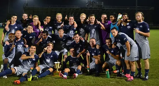 Men's soccer team celebrating around Dennis Viollet Trophy