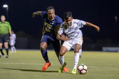 UNF men's soccer player dribbles the ball by opponent