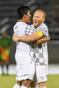 UNF men's soccer teammates celebrate with a hug