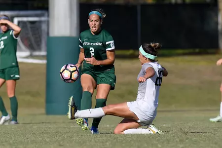 UNF women's soccer player slide kicks the ball