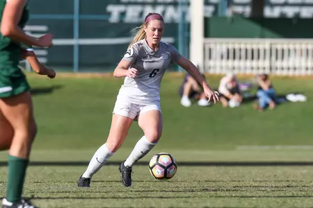 UNF women's soccer player dribbles the ball against opponent