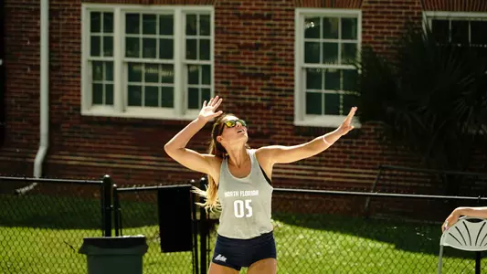 UNF beach volleyball player serves the ball