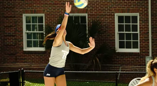 UNF beach volleyball player makes a jump-serve