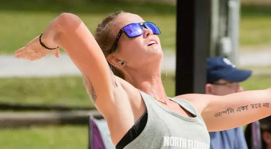 UNF beach volleyball player serves the ball