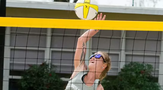 UNF volleyball player spikes the ball