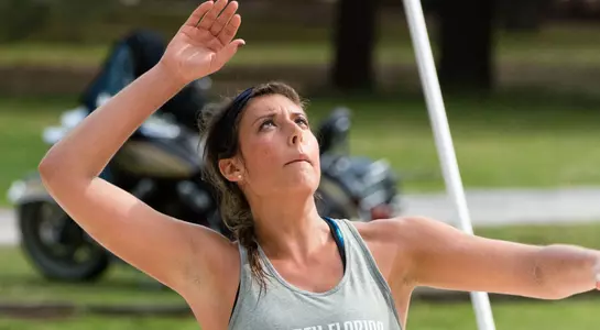 UNF beach volleyball player throws up the ball for a serve