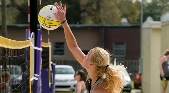 UNF beach volleyball player spikes the ball