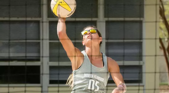 UNF beach volleyball player spikes the ball