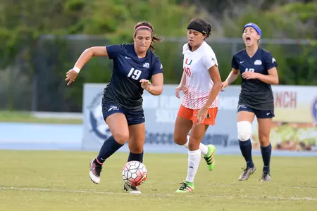 UNF women's soccer player dribbles the ball up the field against an opponent