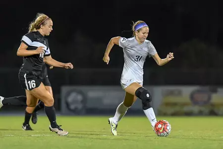 UNF women's soccer player dribbles up the field against opponent