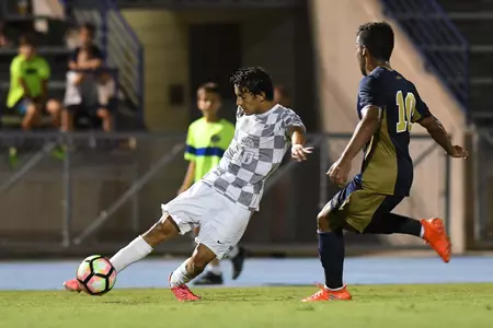 UNF men's soccer player makes a slide pass