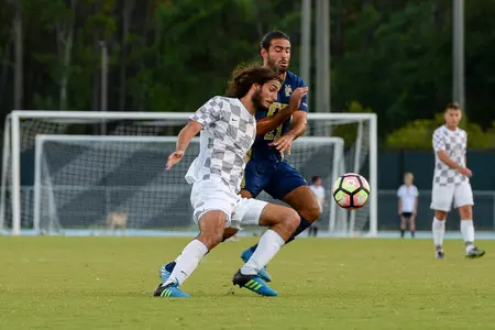 UNF men's soccer player fights for possession of ball against opponent