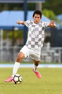 UNF men's soccer player dribbles up the field