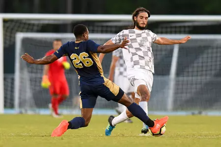 UNF men's soccer player makes a tackle for the ball against opponent