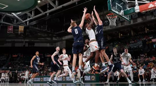 A pair of North Florida players jump and block a shot by a Miami player
