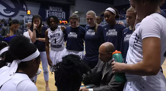Women's basketball huddles in a timeout.