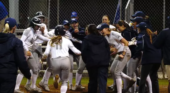 The softball team celebrates at the plate as a Kelley hit a walk-off home run to beat Kansas.