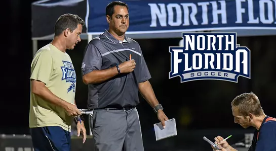 UNF men's soccer coach Derek Marinatos chats with his coaching staff before the game