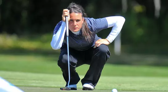 Megan Wilshire kneels down and lines up a putt on the green