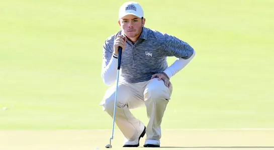 Andrew Alligood kneels beside the green to lineup up a putt