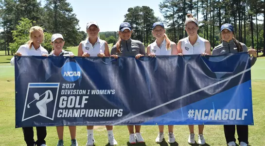 The North Florida women's golf team poses with NCAA Tournament banner beside the green at UGA Golf Course