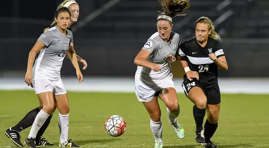 Kelli Crowley dribbles soccer ball away from Wofford player