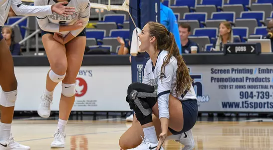 Madilyn McCarty drops to the floor to celebrate during a volleyball match.