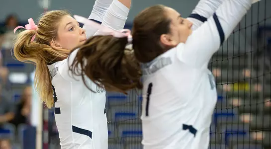 Taryn Griffey and Solimar Cestero leap to block an attack attempt at the net.
