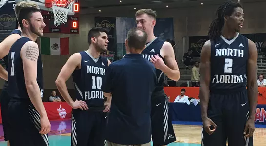 Coach Driscoll stands in huddle with game starters against Southern Miss in Cancun