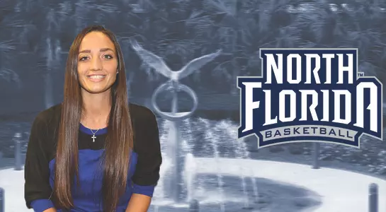 Women's basketball announces Kayla Oxenrider as assistant coach. She sits in front of the Osprey Fountain