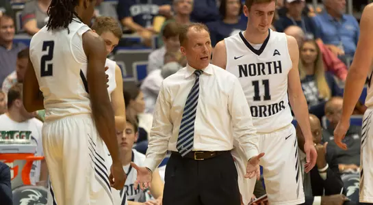 Coach Driscoll stands in the middle of the team huddle on the floor
