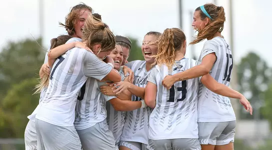 Women's soccer players celebrate a match victory with a group hug