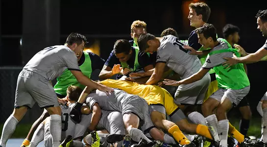 Men's soccer celebrates after a goal.
