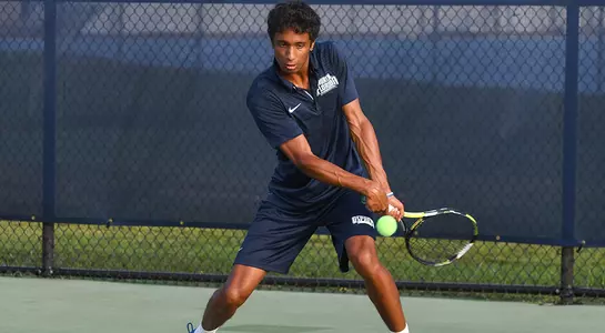 Deshmukh eyes an oncoming tennis ball, preparing to hit a two-handed backhand.