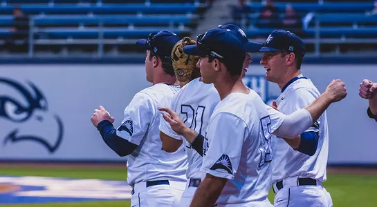 North Florida Baseball team stands outside the dugout.