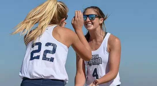 beach volleyball players carolyn cain and blaire register celebrate a point.