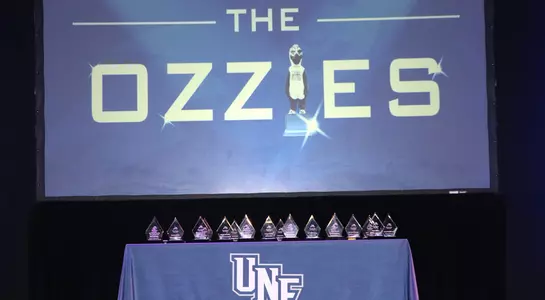 Ozzie awards show trophy table and logo on backdrop of screen