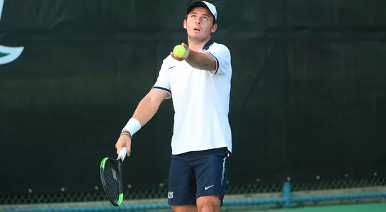 Charley Castaing tosses up the ball to hit a serve.