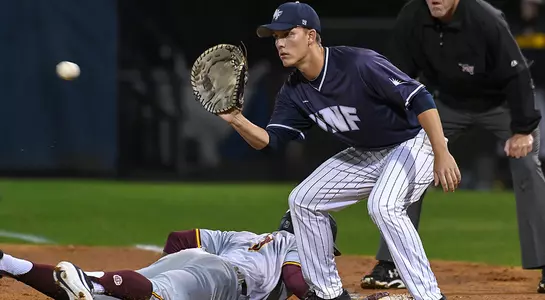 baseball player Alex Reynolds receiving a ball at first while player dives back