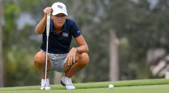 Sara McKevitt kneels and lines up a putt on the green