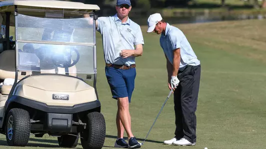 Coach Scott Schroeder and Nick Infanti stand together by the golf cart