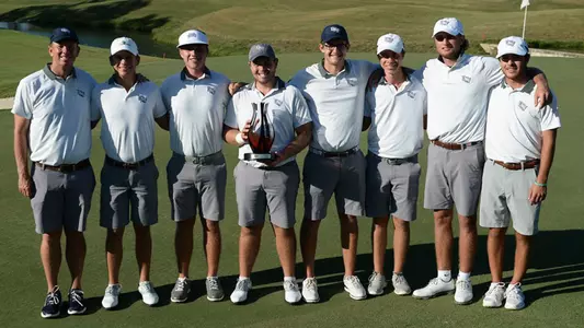 Men's golf team poses as a group by the side of the green