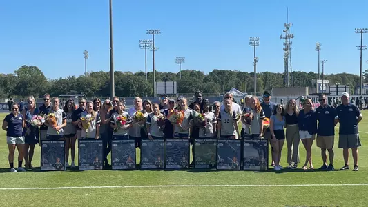 The 2021 women's soccer senior class poses with family on the sideline