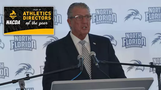 Lee Moon stands behind a podium next to the NACDA Athletic Director of Year logo graphic
